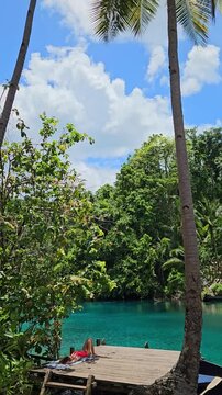 Woman sunbathing near Paisu Pok lake with blue water in Sulawesi, Banggai
