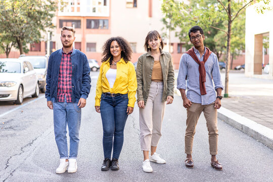 Confident multiethnic young friends standing together on a city street. Diverse millennials and gen z face the camera in a relaxed urban neighborhood. Inclusion concept