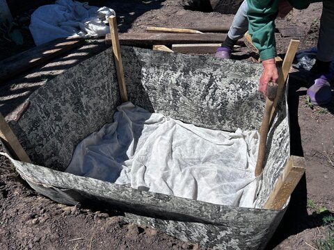Preparing a raised garden bed lined with landscape fabric before adding soil. Ideal for gardening guides, landscaping ads, blogs, and social media.