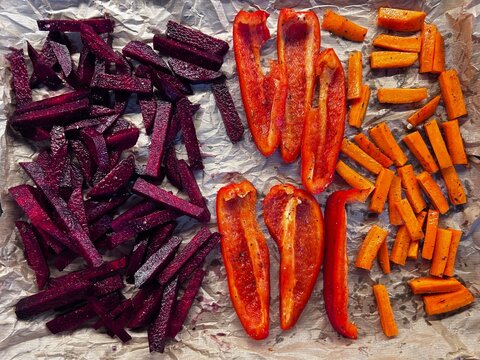 Colorful raw beetroot, red bell pepper, and carrot sticks arranged on baking paper before roasting. Ideal for healthy food ads, recipe blogs, menus, and social posts.