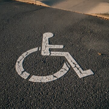 Cracked White Wheelchair Symbol on Asphalt Surface in Urban Setting