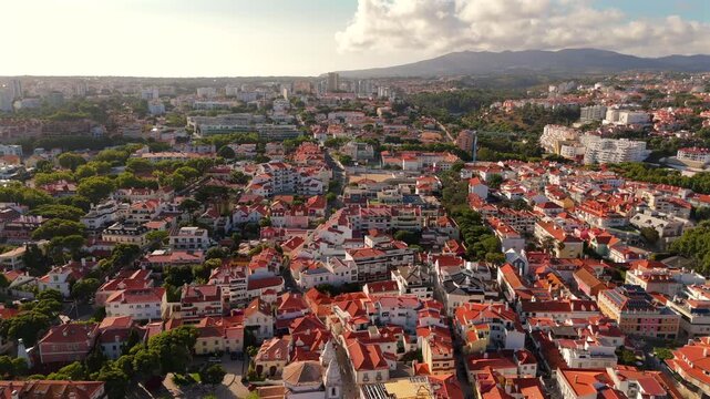 A drone flies forward over a residential town with dense terracotta rooftops and buildings