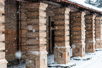 Obraz premium brick colonnade of old building during snowfall