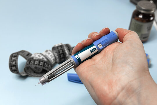Hand holding Ozempic injection pen for diabetes treatment.