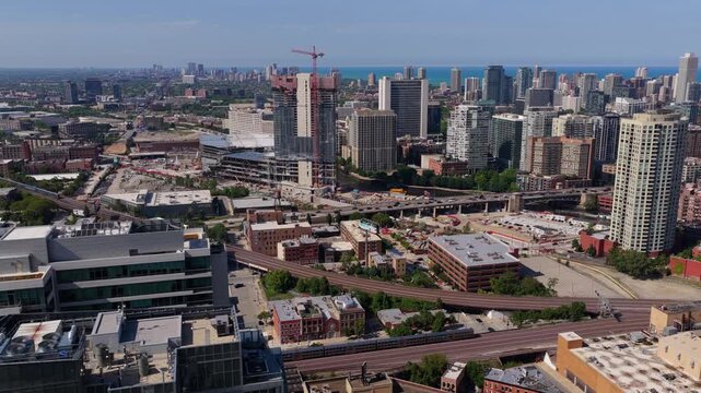 Metra train traveling through Chicago's West Loop neighborhood towards downtown with skyscrapers under construction in a sunny summer day