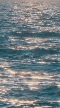 Sparkling sea waves reflecting sunset light in slow motion, Vertical video for smartphone footage