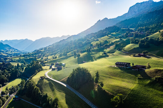 Aerial summer view of Erlenbach im Simmental - winding country road, farmhouses and sunlit alpine meadows