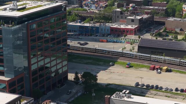 Metra train passing next to Fulton Market District building with green roof in Chicago, modern urban architecture and sustainable design principles in city landscape