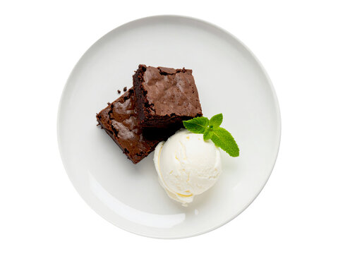 Two rich chocolate brownies are served on a white plate with a scoop of vanilla ice cream and a sprig of mint.
