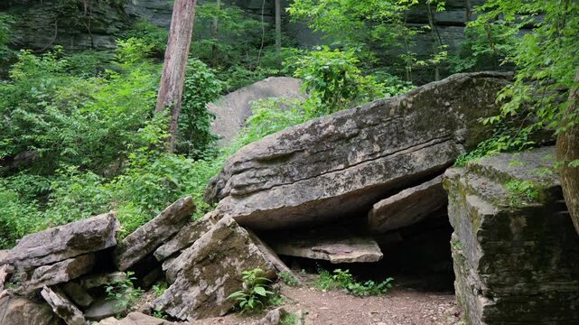 Rugged, dry rocky Arkansas creek bed surrounded by dense green forest foliage and towering limestone bluff walls along a wilderness hiking trail