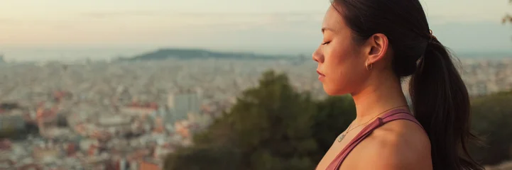 Fotobehang Lotusbloem Close-up of girl meditating while sitting on viewing platform at dawn. Panoramic  © Andrii Nekrasov