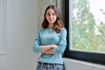 Obraz premium Calm teen girl with crossed arms looking at camera