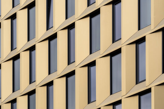 Modern architecture abstract details simplify an urban building facade, where exterior windows and geometry create warm diagonal rhythms across panels