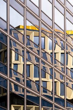 Modern architecture abstract details reflect through an urban building facade, where exterior windows and geometry mirror golden forms and sky