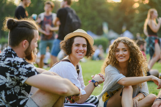 Group of young friends sitting on ground at summer festival.