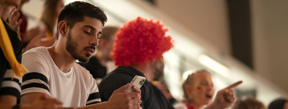 Worried football fans supporting German national team in live soccer match at stadium.