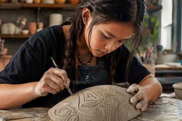 Left handed indigenous youth carving clay in workshop