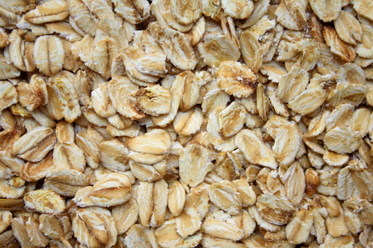 Oat flakes pattern top view. Rolled oats texture macro. Creamy cereal background. Organic breakfast wallpaper. Raw oatmeal backdrop. Wholesome grain layer. Uncooked muesli surface. Healthy nutrition