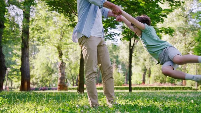 Happy father gently holds cheerful little son and spins around