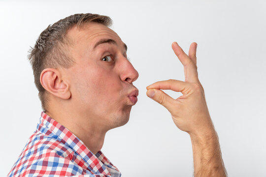 Man in a casual plaid shirt is sending an air kiss with puckered lips and a hand gesture expressing affection or a secret message, looking directly at the camera