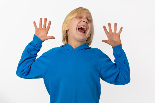 Blonde child wearing a blue hoodie expressing a strong emotion, crying out with an open mouth and outstretched palms against a clear background
