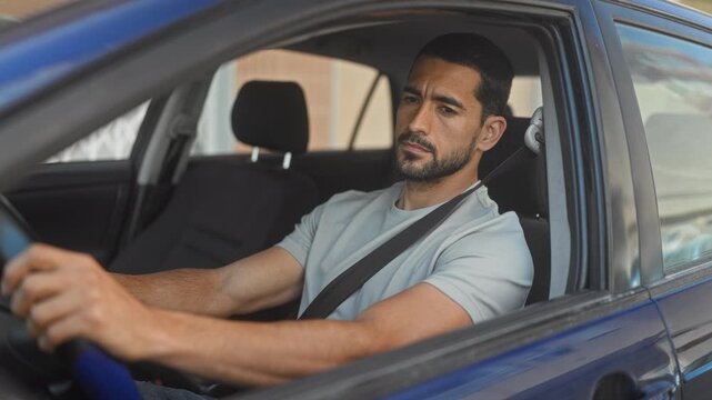 Man with seatbelt resting arm on car door and hand on steering wheel, looking sideways in street; contemplation.