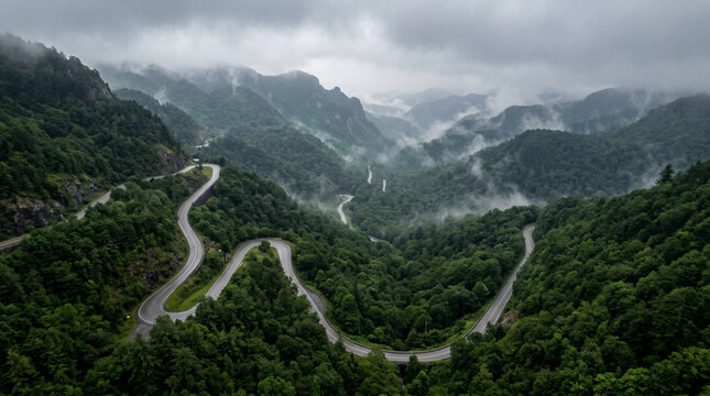Foggy mountain pass road winding through misty hills.