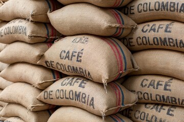 Plakat The Burlap Coffee Sacks Stacked High in a Rustic Colombian Warehouse