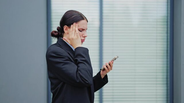 Professional appears worried, experiencing discomfort and stress while checking smartphone. Possible bad news or pressure causes concern, indicating challenging business situation or personal setback.