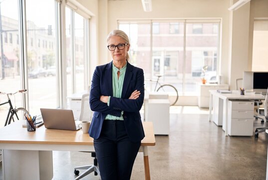Professional mature businesswoman standing in a modern office with arms crossed