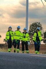 Obraz premium The wind farm crew of four stop while the leader points out tomorrow's machines on the park road under fading skies in pink pastel dusk deep inside a tropical wind energy park image 6447.
