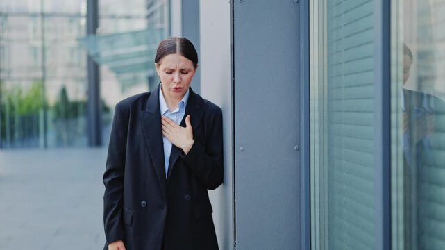 Female professional experiences sudden severe chest pain, possibly heart attack or panic attack, needing support. Urgent health concern, difficult breathing evident. Stressful urban moment.