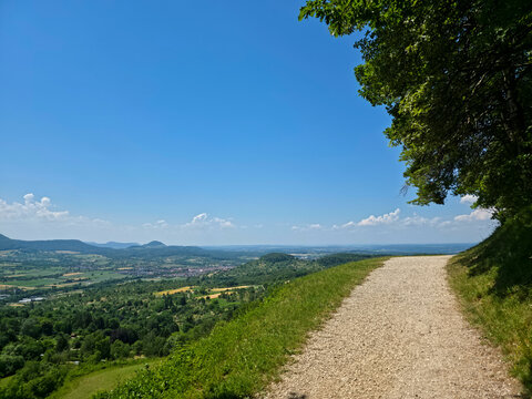 germany, scenic hiking trail alongside lush green trees overlooking the breathtaking swabian alb hills under a perfect summer blue sky