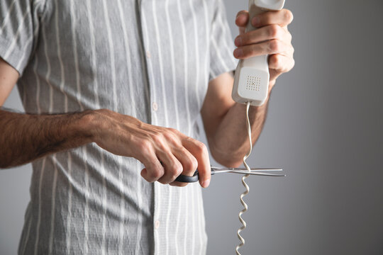 Man cutting landline telephone cord.