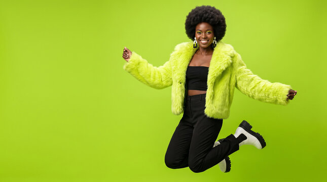 Young woman jumping with joy in a vibrant green studio background