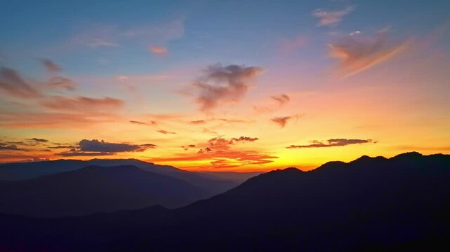 
Aerial Twilight Over the hill. This panoramic aerial photograph captures a vast mountain range at sunset. The sky is ablaze with warm pink and golden tones, casting a soft glow over the rugged peaks.