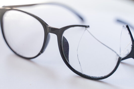Closeup of Broken Eyeglasses with Cracked Lens on White Surface