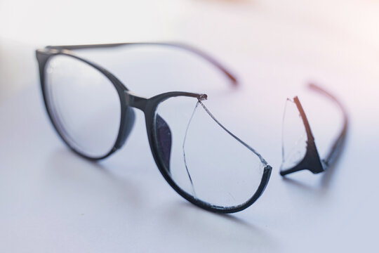 Closeup of Broken Eyeglasses with Cracked Lens on White Surface