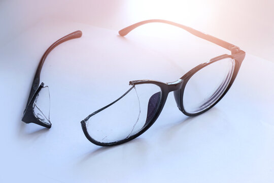 Closeup of Broken Eyeglasses with Cracked Lens on White Surface