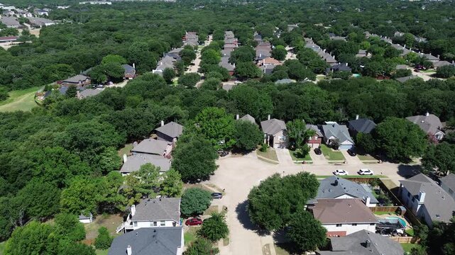 Quiet suburban cul-de-sacs display homes near deep forest lines. Gray peaked roofs complement green backyards and mature oaks, illustrating local community density patterns in Flower Mound, TX