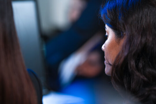 Profile view intense focus. Young female professional deeply absorbed work computer screen late night modern tech hub glow reflects determination concentration project deadline grind.