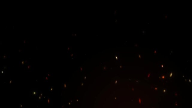 Intense warm fire sparks and embers scattering upwards against dark background in dynamic motion animation