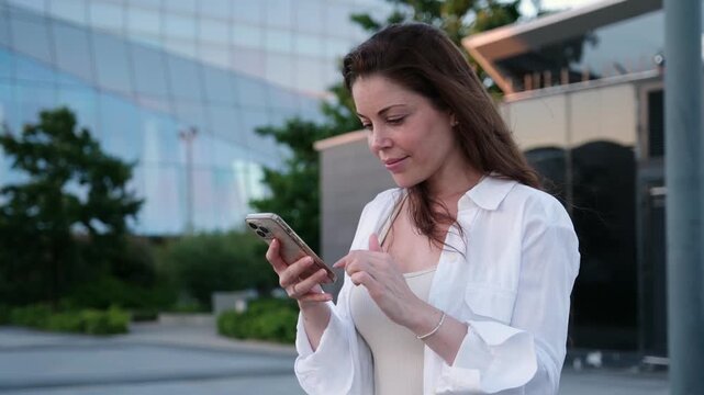 Confident businesswoman browsing social media on her smartphone in a modern city