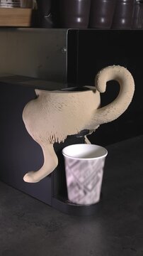 An engineer turns on a coffee machine with a 3D-printed dog body attached.