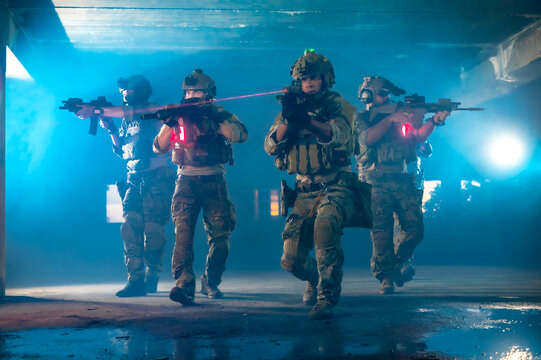 Highly trained suicide squad team in full tactical military uniform and heavily armed with weapons conducting a foot patrol mission inside a ruined abandoned building
