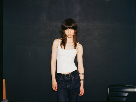 Model stands in a simple outfit against a dark wall