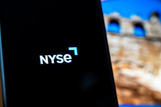 Warsaw, Poland - July 6, 2026: Close-up of the New York Stock Exchange (NYSE) logo displayed on smartphone screen with blurred historical landmark background, symbolizing finance and investment.