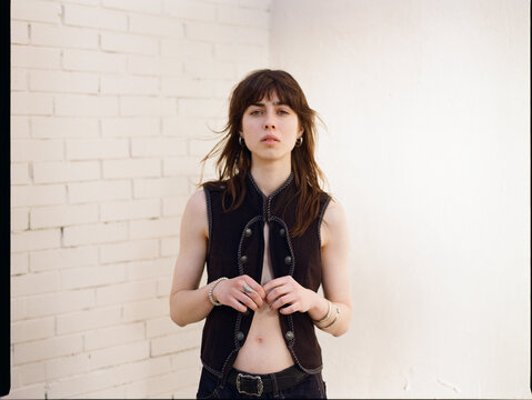 Young woman stands by a white brick wall on street