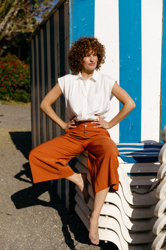 Woman posing by blue striped beach hut