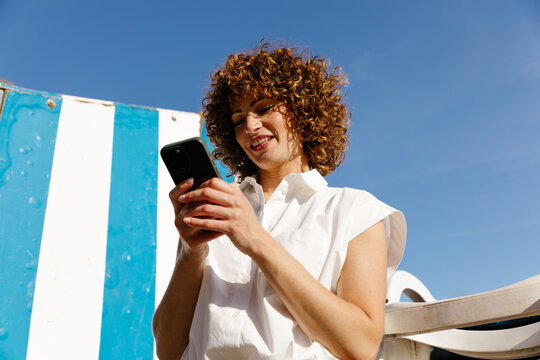 Woman smiling and using smartphone outdoors